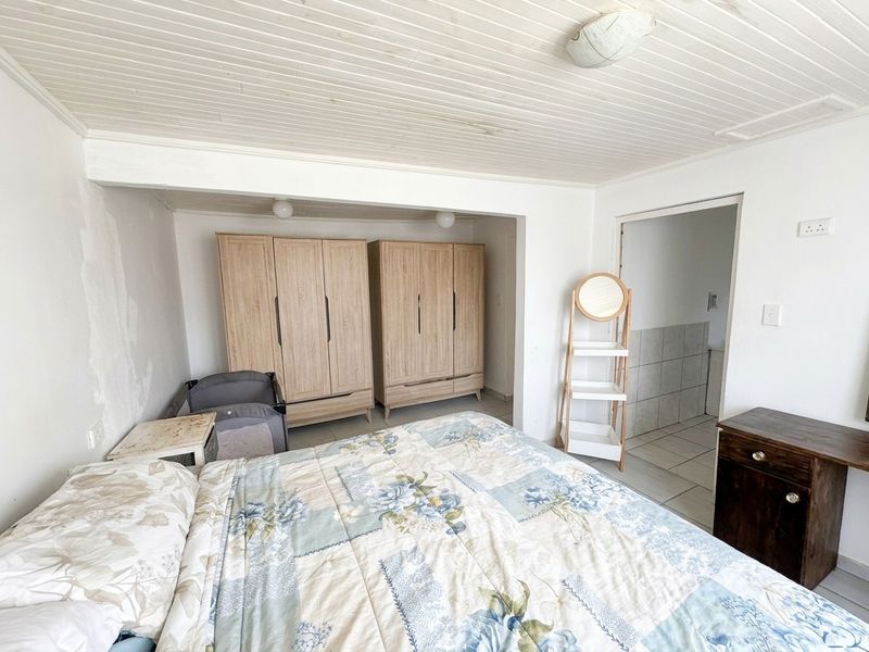 Bedroom featuring built-in wardrobes, timber ceiling, and direct access to an en-suite bathroom. The room requires cosmetic attention to wall finishes.