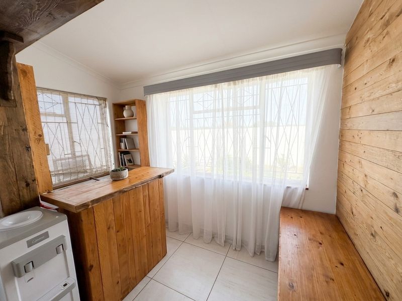 A functional utility space featuring timber wall cladding, built-in wooden cabinetry, and tiled flooring, offering a rustic aesthetic with secure window treatments.
