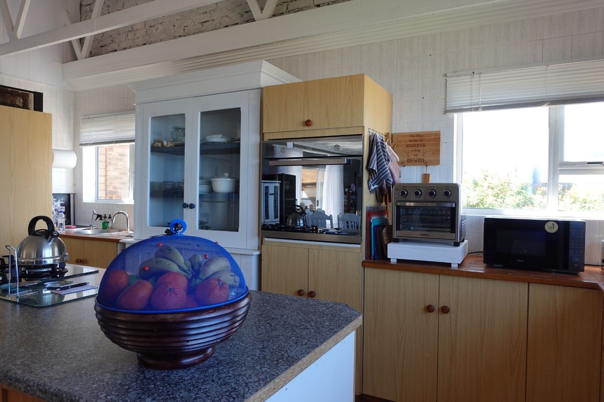 A functional kitchen featuring laminate cabinetry, granite countertops, a built-in oven, and exposed roof trusses, offering a practical layout with ample storage space.
