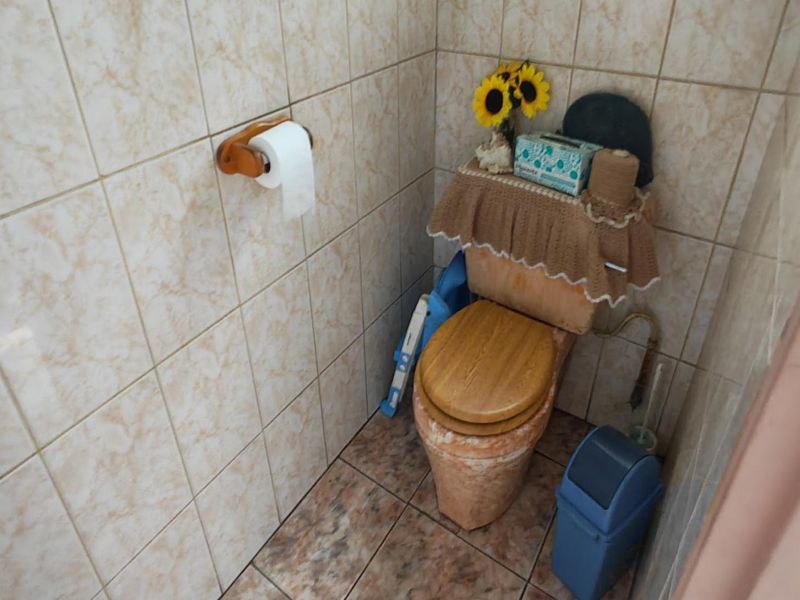 A compact bathroom featuring dated ceramic wall and floor tiling with a standard toilet fixture.