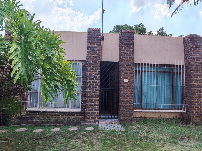 Front facade of a face brick house featuring a secure entrance gate and protective burglar bars on the windows.