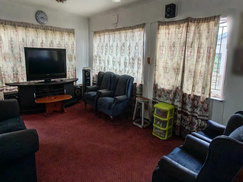 A living room featuring wall-to-wall carpeting and multiple windows with curtains, providing a functional space for relaxation.