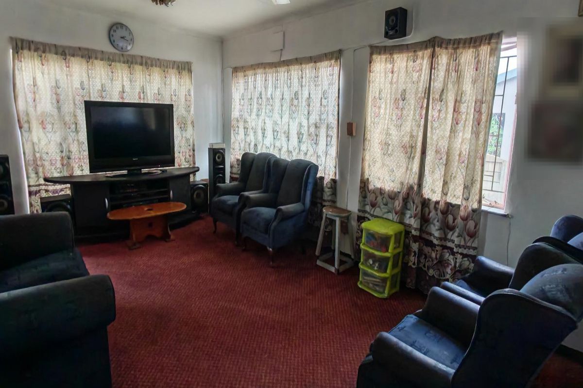 A living room featuring wall-to-wall carpeting and multiple windows with curtains, providing a functional space for relaxation.