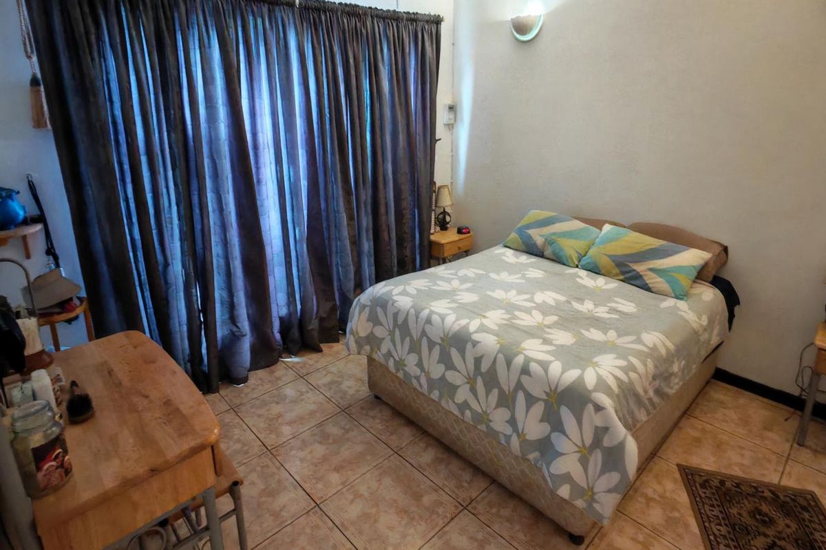 A functional bedroom featuring tiled flooring and a wall-mounted light fixture, providing a neutral base for potential interior updates.
