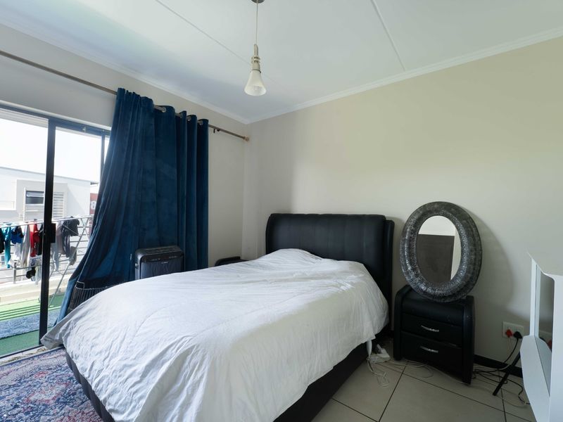 A bedroom featuring tiled flooring, a coved ceiling, and a sliding glass door providing access to an outdoor balcony area.