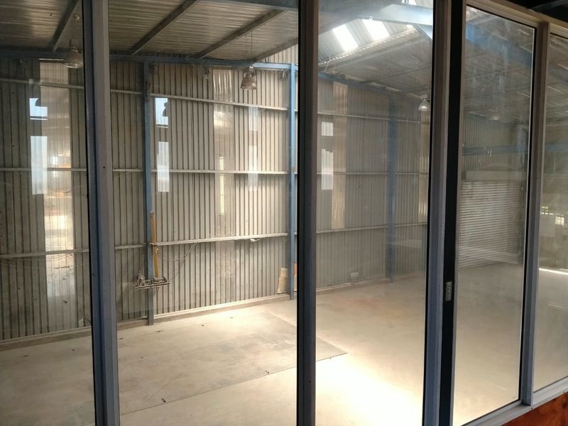 Spacious industrial utility area featuring corrugated metal walls, exposed steel framing, concrete flooring, and natural light from overhead skylights.