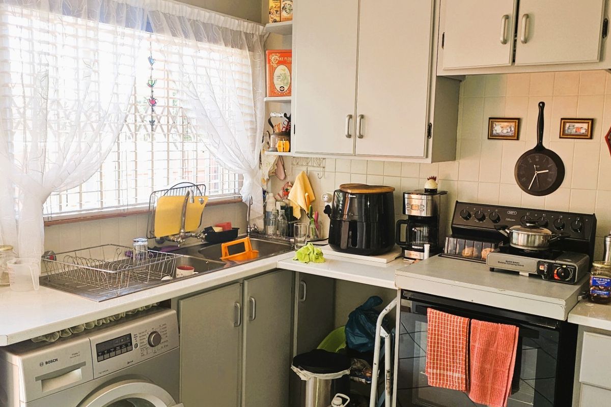 A functional kitchen featuring built-in cabinetry, a tiled backsplash, and a freestanding oven, offering a practical layout with natural light from the window.