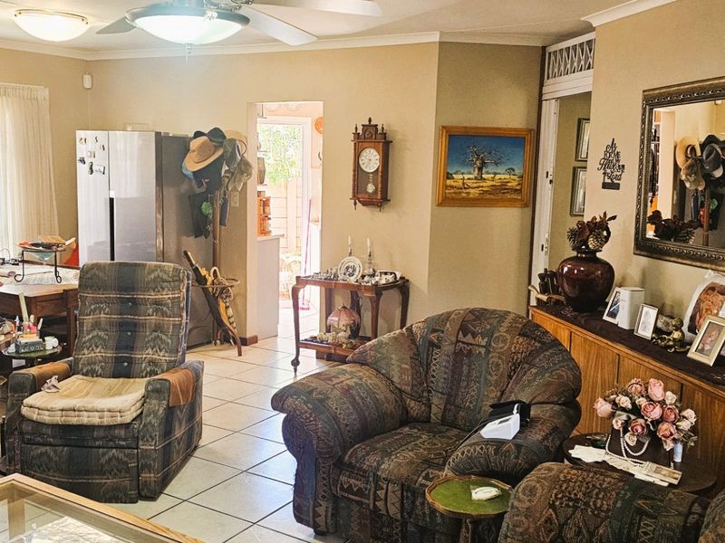 A spacious living area featuring tiled flooring, coved cornicing, and a ceiling fan, providing a comfortable and functional space for relaxation.