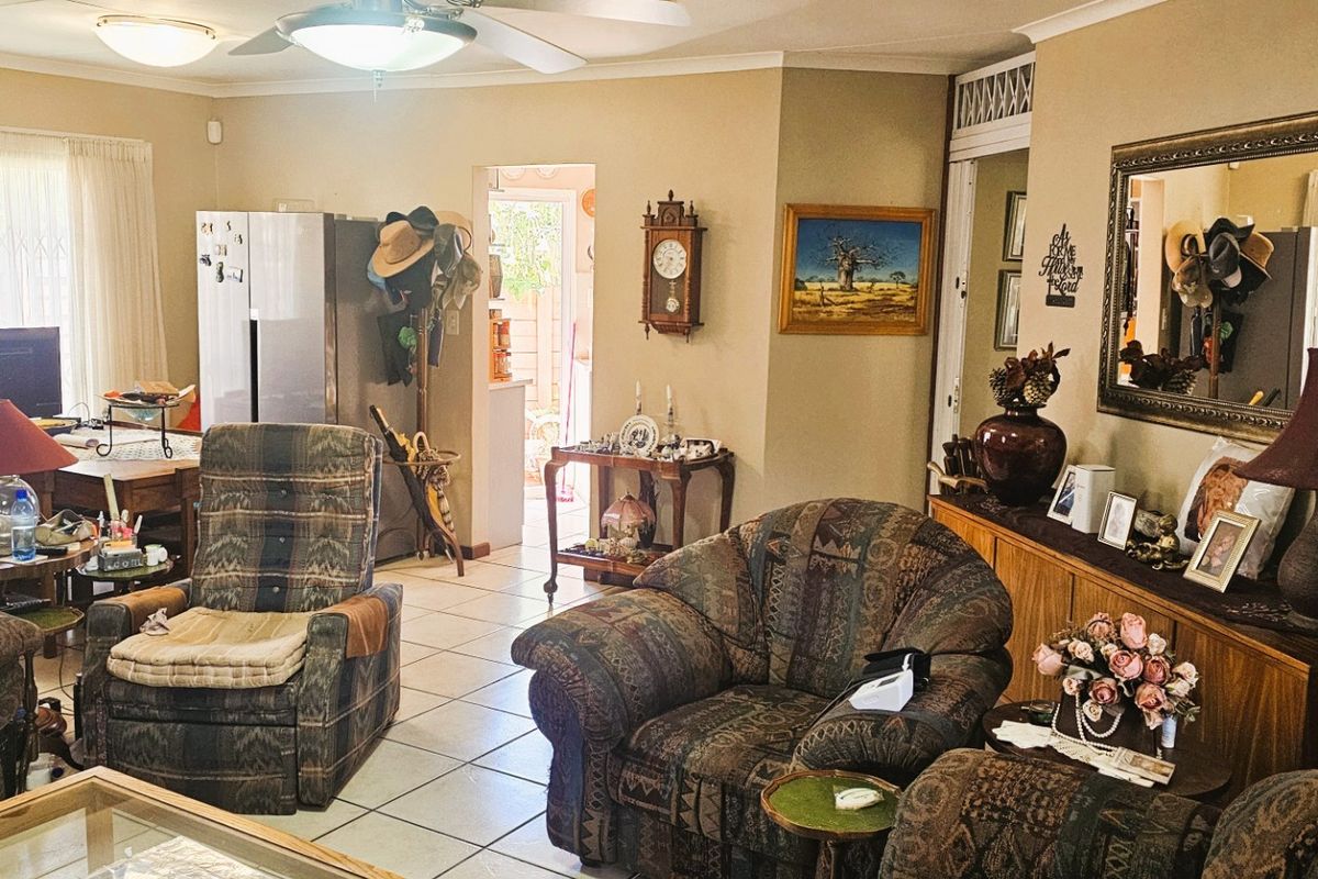 A spacious living area featuring tiled flooring, coved cornicing, and a ceiling fan, providing a comfortable and functional space for relaxation.