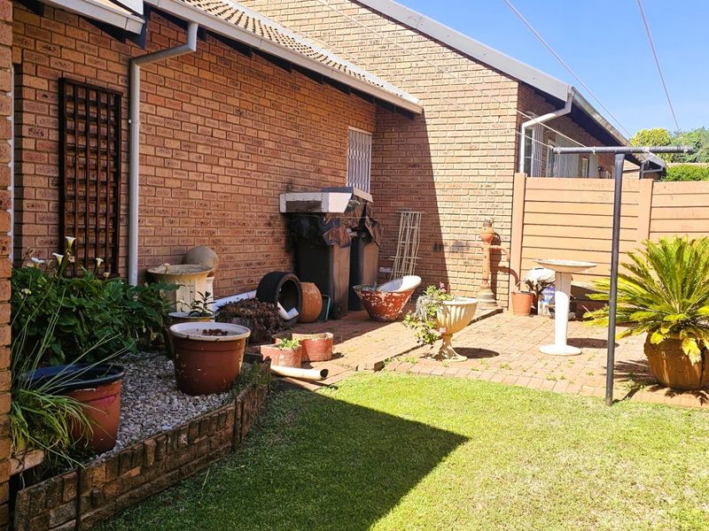 A private rear courtyard featuring brick paving, a small lawn area, and perimeter fencing, offering a functional outdoor space for the townhouse.