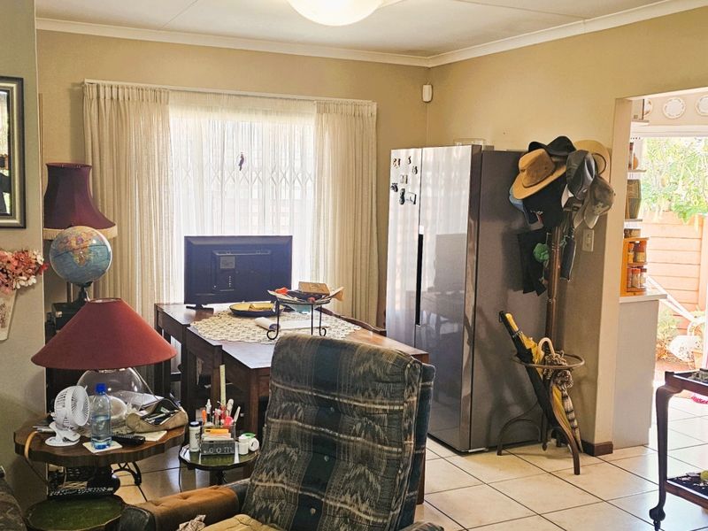 Open plan living area featuring tiled flooring and access to an outdoor space through a sliding door with security gate.