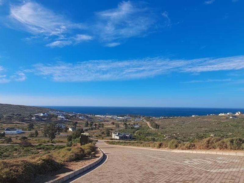 A scenic elevated view overlooking the coastal landscape and surrounding residential area from a paved road.