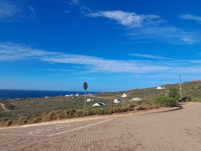 A scenic elevated view overlooking the coastal landscape and surrounding residential area from a paved road.