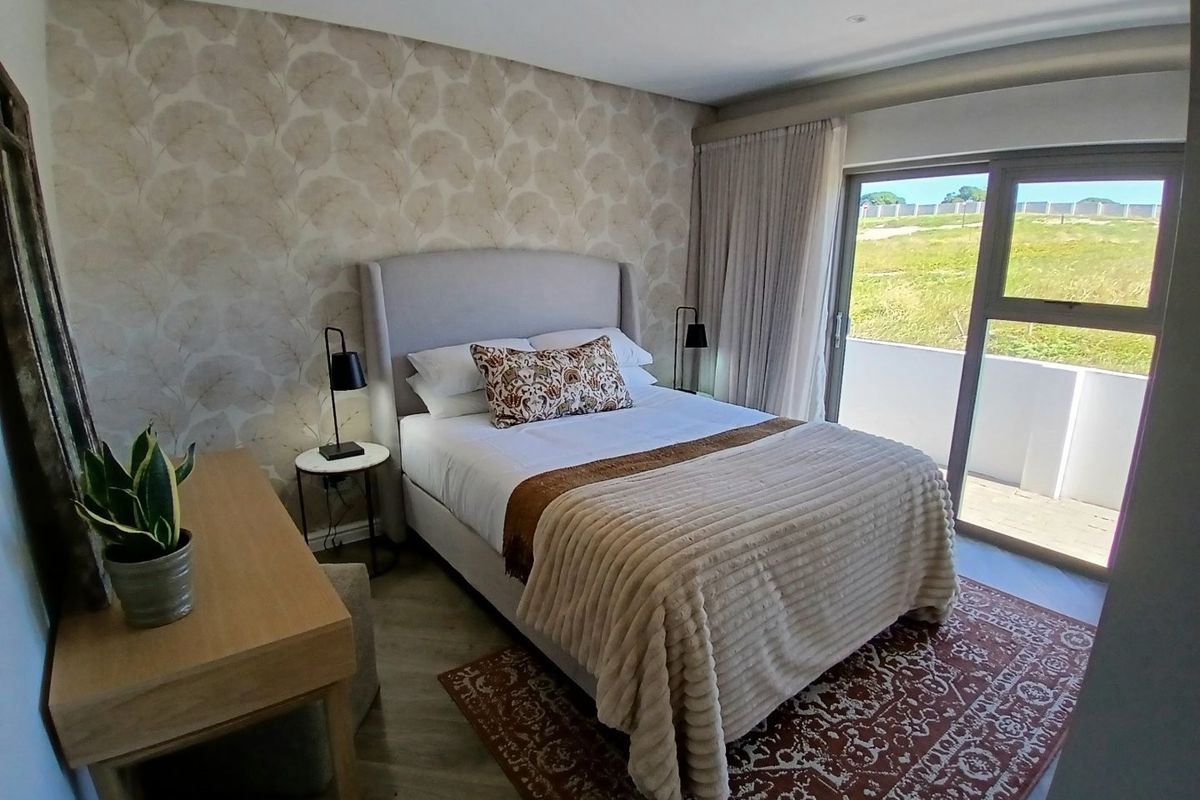 A well-maintained bedroom featuring patterned wallpaper, recessed lighting, and a large sliding glass door providing access to an outdoor balcony area.