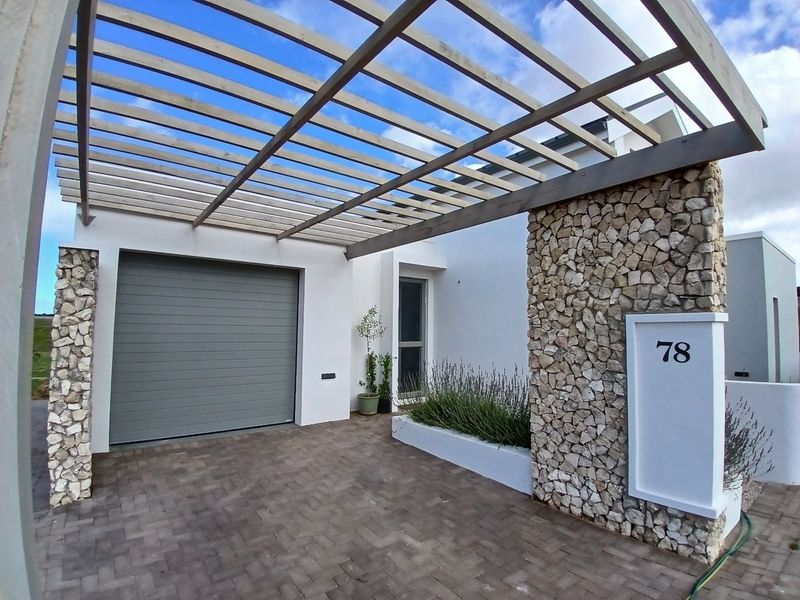 Modern front facade featuring a timber pergola, stone-clad pillars, paved driveway, and a secure sectional garage door.