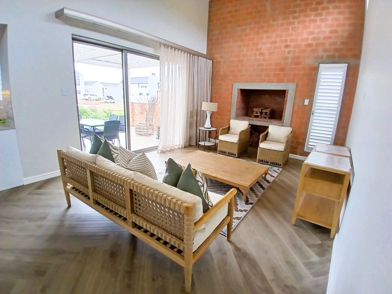 Spacious living room featuring an exposed brick wall, built-in fireplace, herringbone flooring, and large sliding glass doors leading to an outdoor patio area.