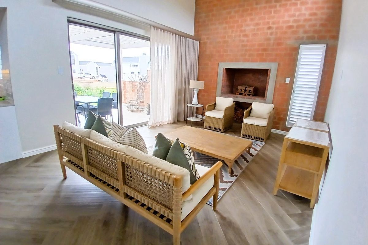 Spacious living room featuring an exposed brick wall, built-in fireplace, herringbone flooring, and large sliding glass doors leading to an outdoor patio area.