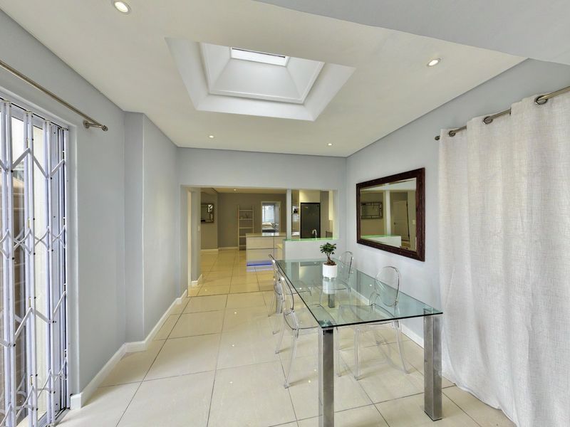 Bright dining area featuring tiled flooring, a central skylight, and a convenient pass-through window connecting to the kitchen space.