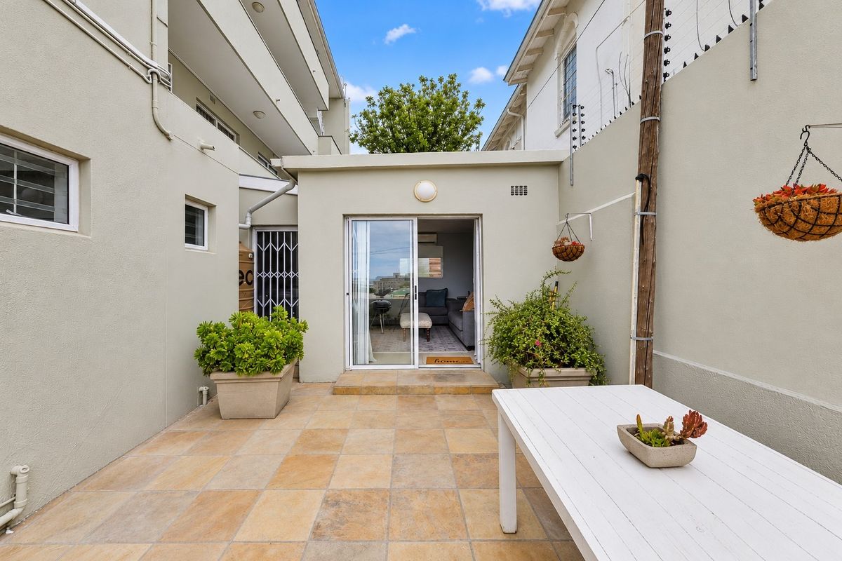 A private rear patio area featuring tiled flooring, secure sliding door access, and perimeter electric fencing, providing a functional outdoor space.