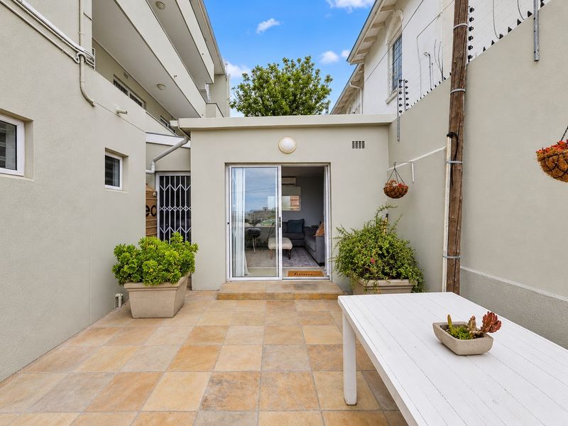 A private rear patio area featuring tiled flooring, secure sliding door access, and perimeter electric fencing, providing a functional outdoor space.