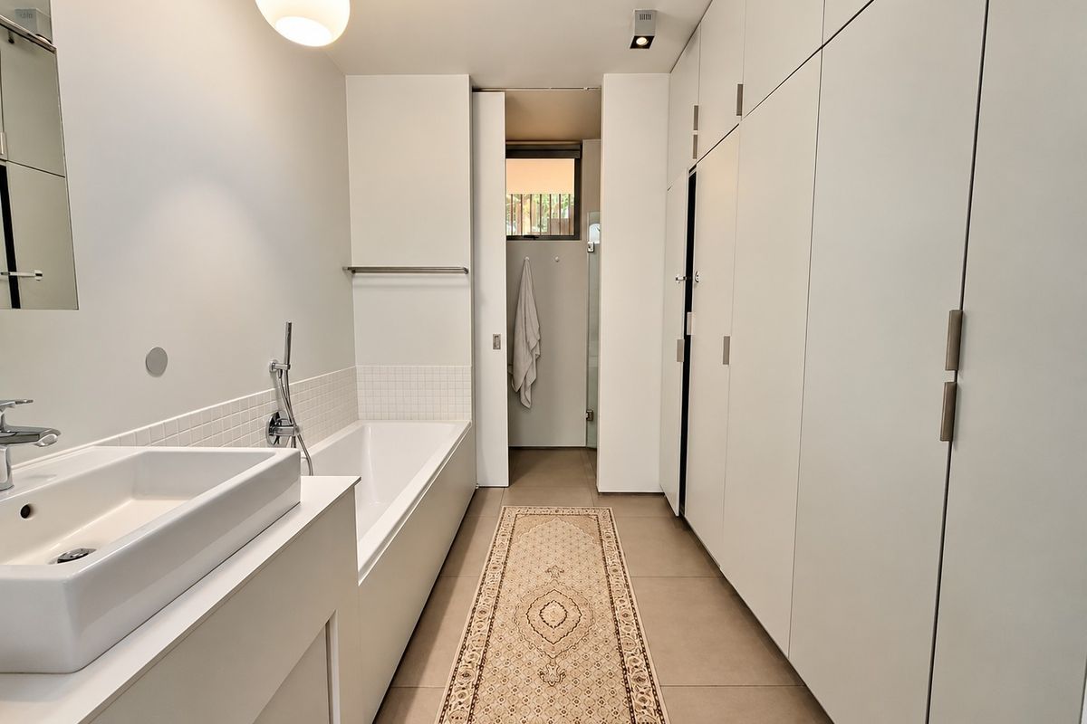 Modern bathroom featuring a sleek bathtub, integrated basin, and extensive built-in cabinetry providing ample storage space.