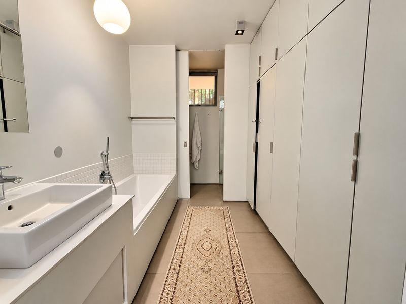 Modern bathroom featuring a sleek bathtub, integrated basin, and extensive built-in cabinetry providing ample storage space.