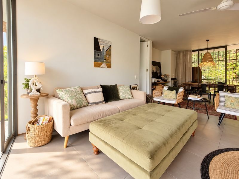 Bright open-plan living and dining area featuring large sliding glass doors, neutral tiled flooring, and modern ceiling fan, creating a seamless indoor-outdoor flow.