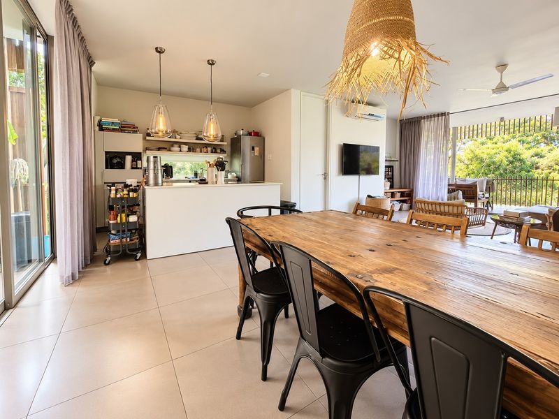 Spacious open-plan living and dining area featuring modern tiled floors, a sleek kitchen island, and seamless access to a private balcony through sliding glass doors.
