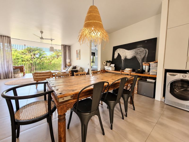 Spacious open-plan living and dining area featuring tiled floors, a ceiling fan, and seamless access to a private balcony through large sliding glass doors.