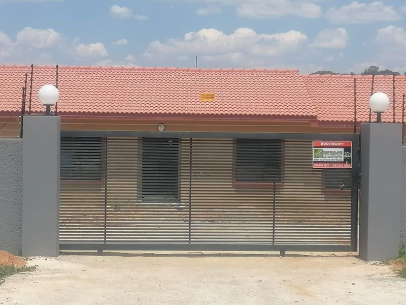 Front view of the property featuring a modern sliding gate, electric fencing, and a tiled roof with security shutters on the windows.