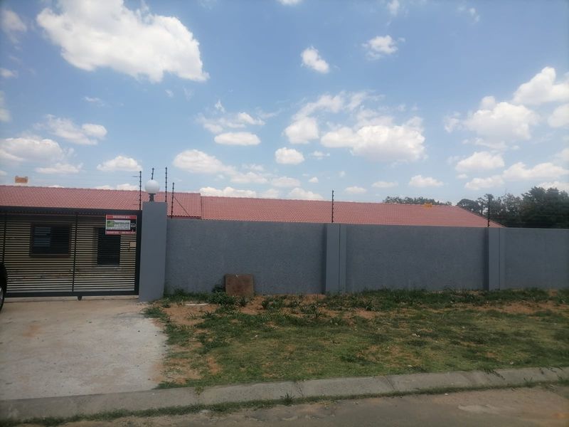 Front exterior view of the property featuring a secure perimeter wall with electric fencing, a sliding gate, and a tiled roof.