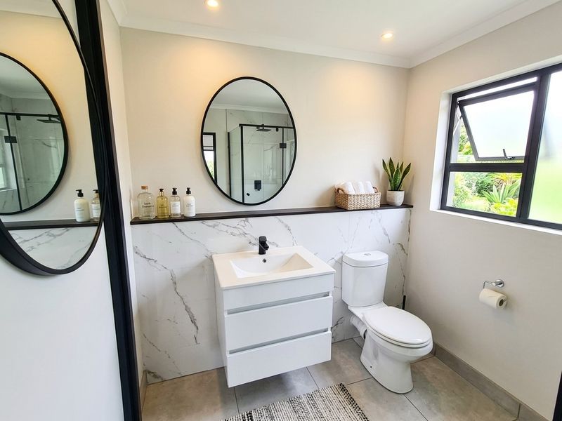 Modern bathroom featuring a sleek vanity with marble-look tiling, black fixtures, and a contemporary mirror, creating a clean and well-maintained space.