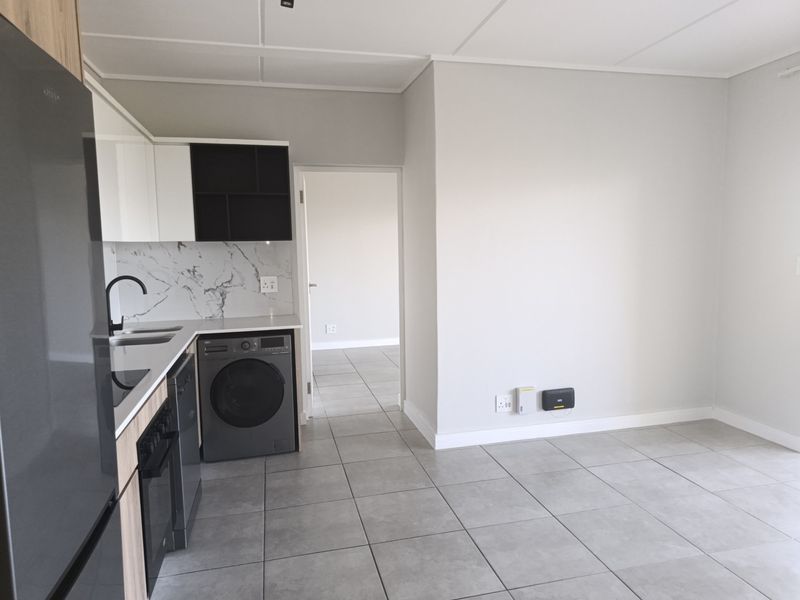 Modern open-plan kitchen featuring sleek cabinetry, marble-look splashback, and tiled flooring, seamlessly flowing into the adjacent living area.