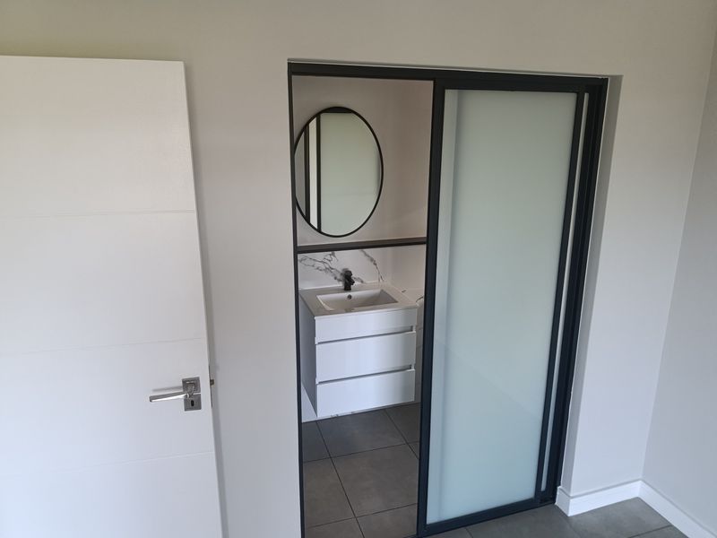 Modern bathroom featuring a sleek vanity with marble-look splashback, contemporary basin, and a sliding door entry.