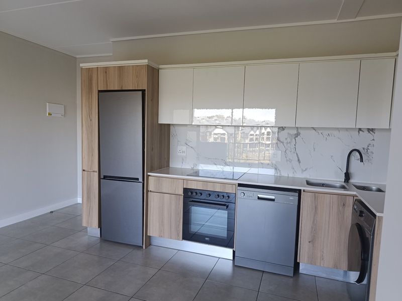Modern kitchen featuring sleek wood-grain and white cabinetry, marble-look splashback, integrated oven, hob, and high-quality tiled flooring in an open-plan layout.