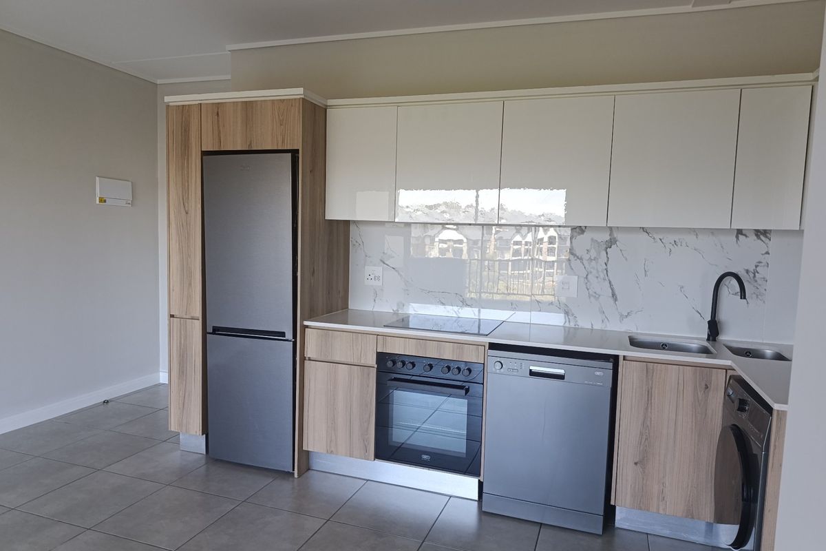 Modern kitchen featuring sleek wood-grain and white cabinetry, marble-look splashback, integrated oven, hob, and high-quality tiled flooring in an open-plan layout.