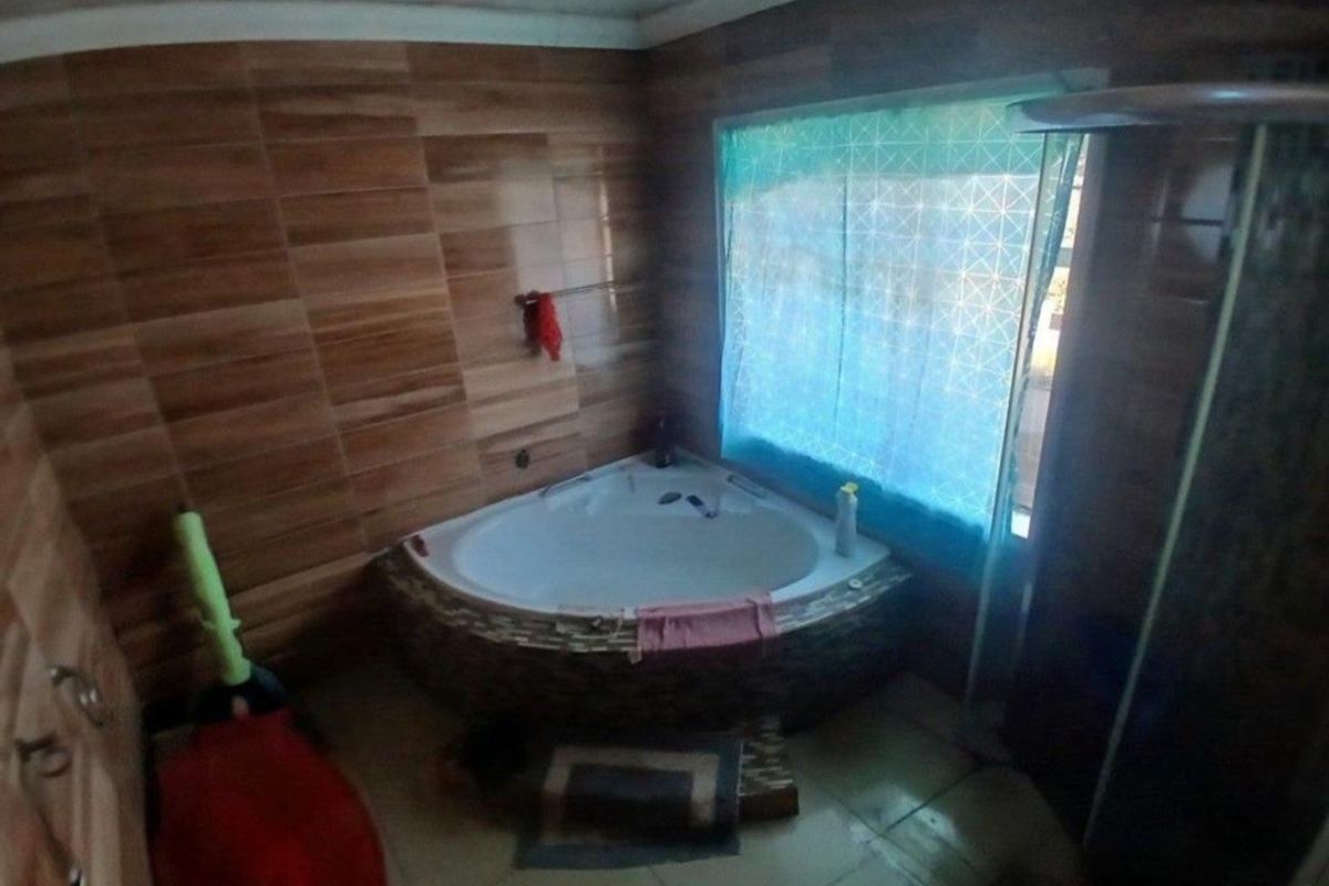 A bathroom featuring a corner bathtub with tiled surround, wall tiling, and a separate shower enclosure.