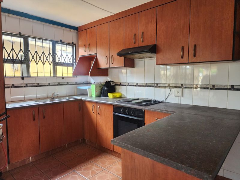 Functional kitchen featuring wood-look cabinetry, built-in oven and hob, tiled backsplash, and ample counter space, offering a solid foundation for modern updates.