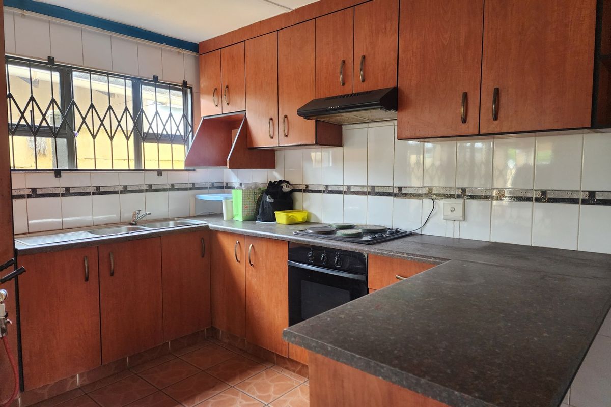 Functional kitchen featuring wood-look cabinetry, built-in oven and hob, tiled backsplash, and ample counter space, offering a solid foundation for modern updates.