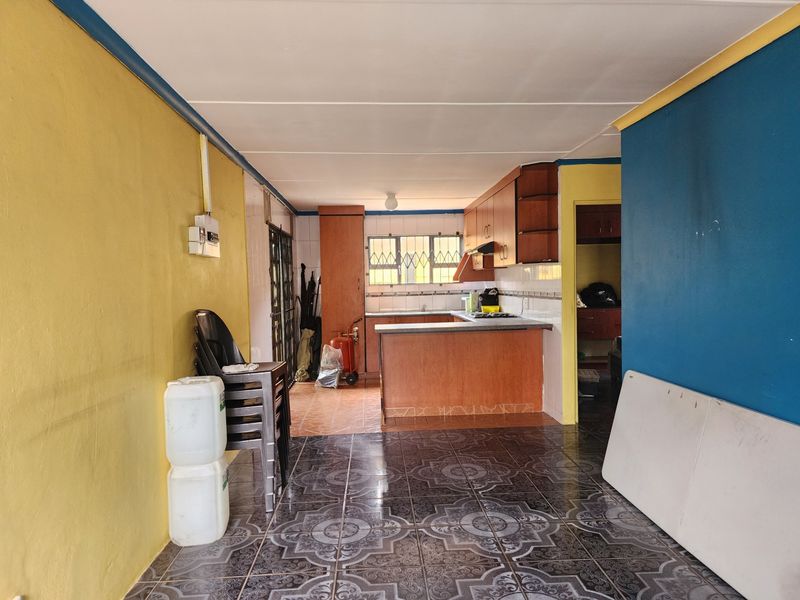 Open plan kitchen area featuring built-in cabinetry, tiled flooring, and a breakfast counter, offering a functional layout ready for modernization.