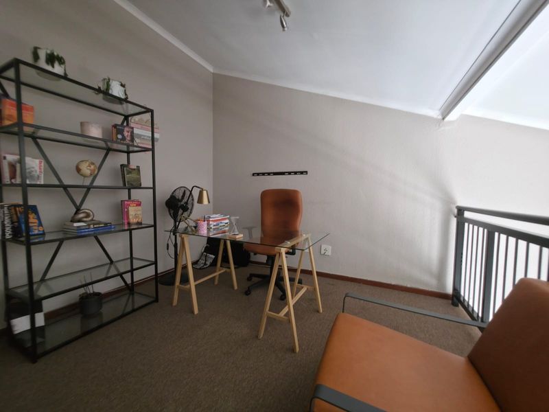 A functional home office space featuring a sloped ceiling and a metal balustrade overlooking the lower level.