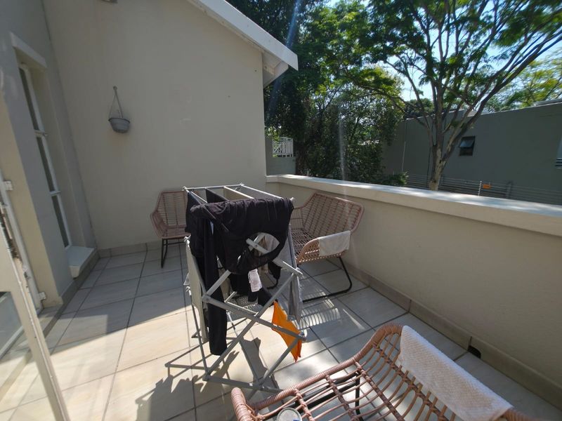 A private balcony featuring tiled flooring and a parapet wall, providing an outdoor space accessible via a sliding door.