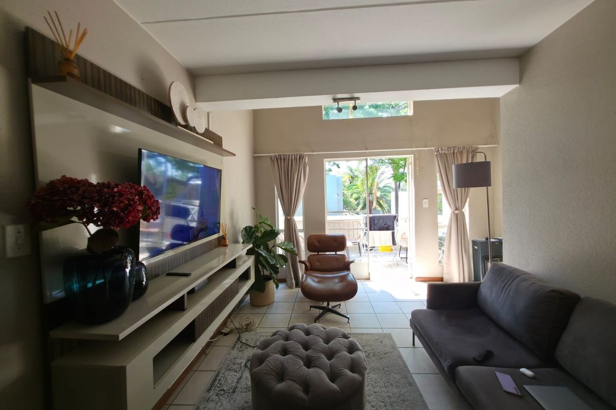 A well-lit living room featuring a built-in media unit, tiled flooring, and a sliding glass door leading to an outdoor patio area.
