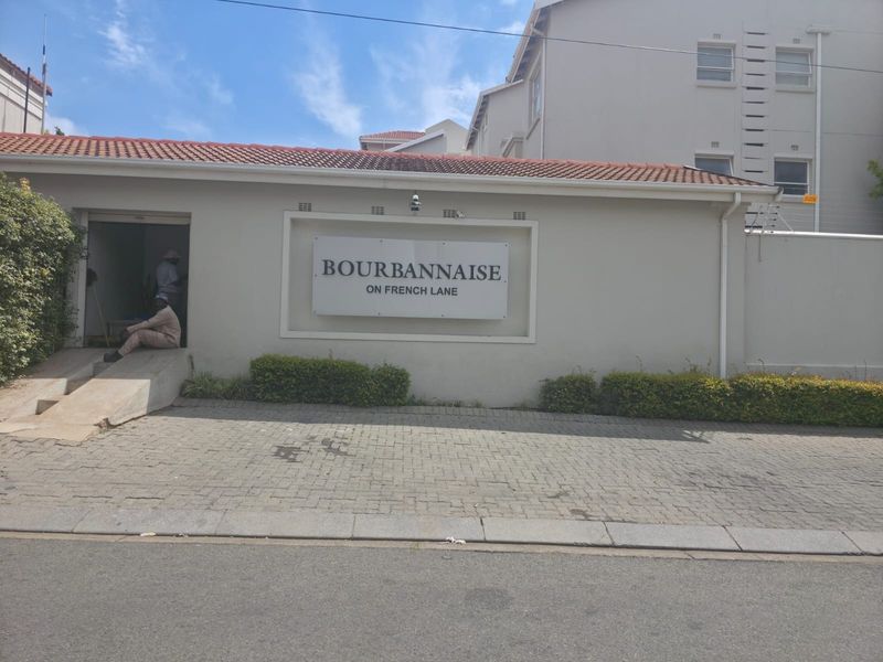 Front entrance view of Bourbannaise on French Lane, featuring a paved driveway, complex signage, and a well-maintained exterior facade.