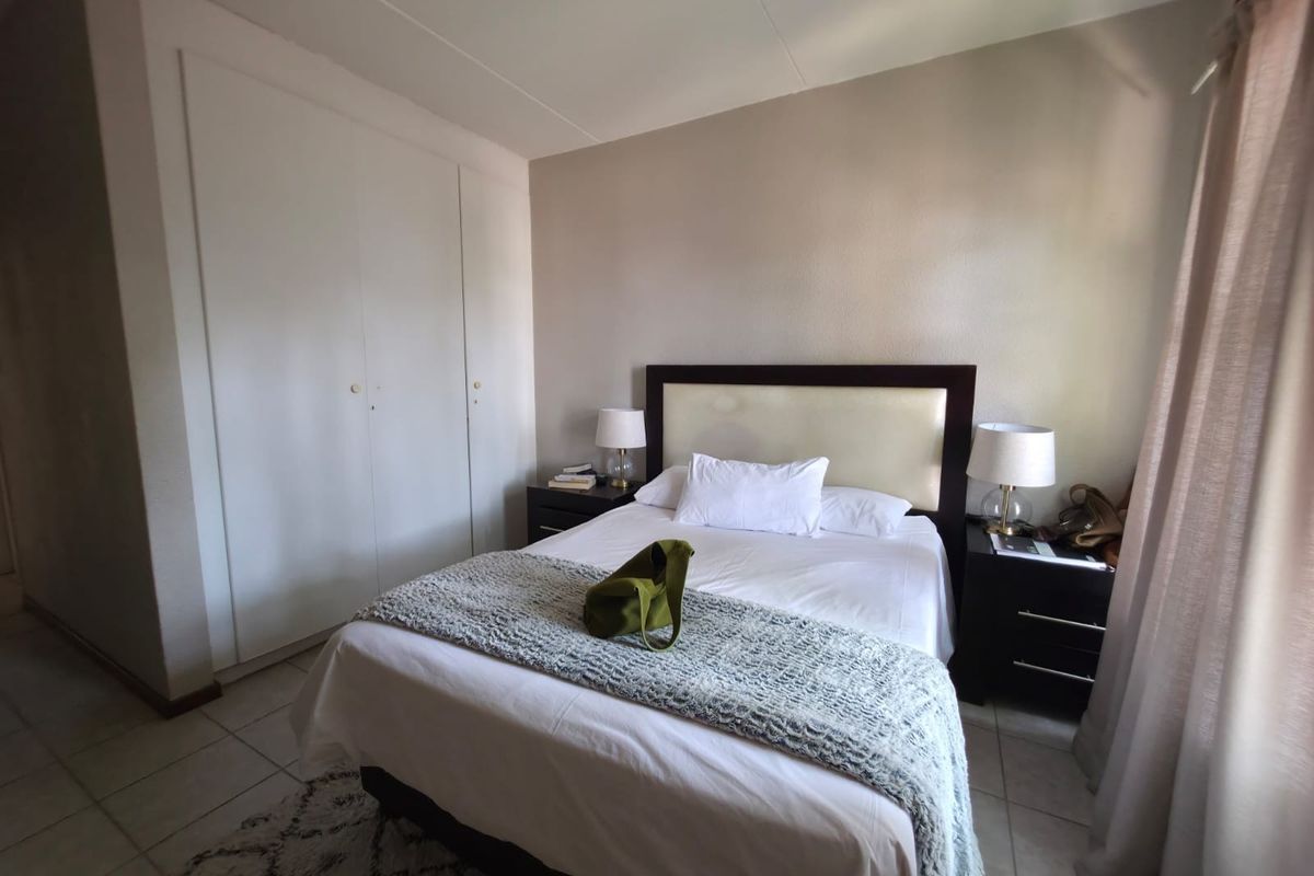 A functional bedroom featuring built-in cupboards and tiled flooring, offering a neutral space ready for personalization.