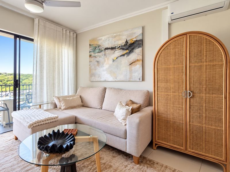 A bright and well-maintained living room featuring a split-system air conditioner, ceiling fan, and large sliding glass doors leading to an outdoor balcony.