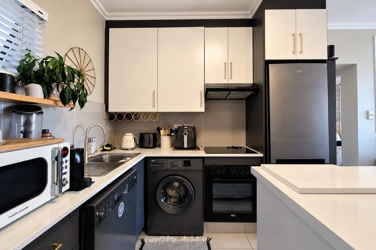 Modern kitchen featuring sleek two-tone cabinetry, stone countertops, integrated appliances, and a functional layout with a built-in oven and hob.