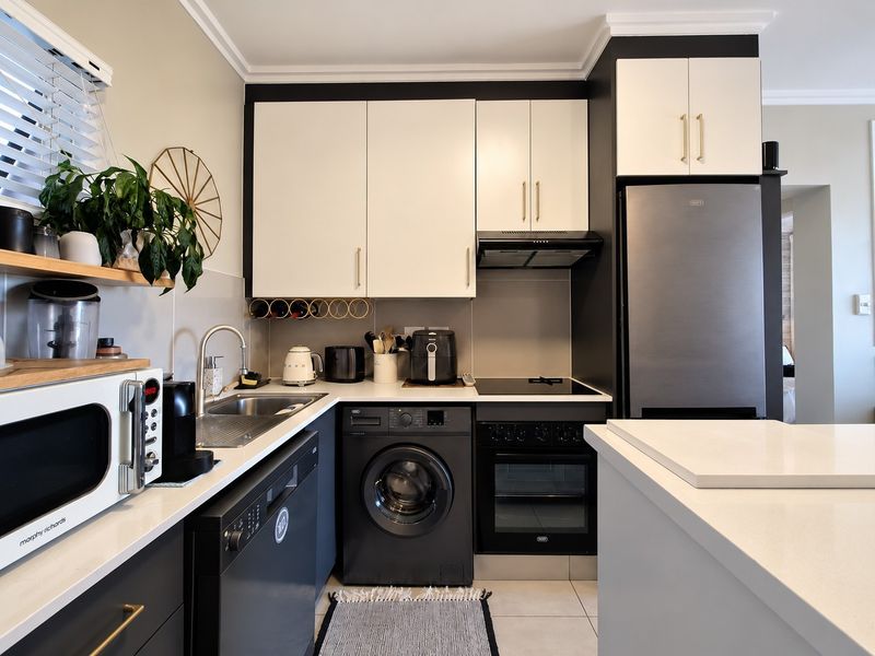 Modern kitchen featuring sleek two-tone cabinetry, stone countertops, integrated appliances, and a functional layout with a built-in oven and hob.