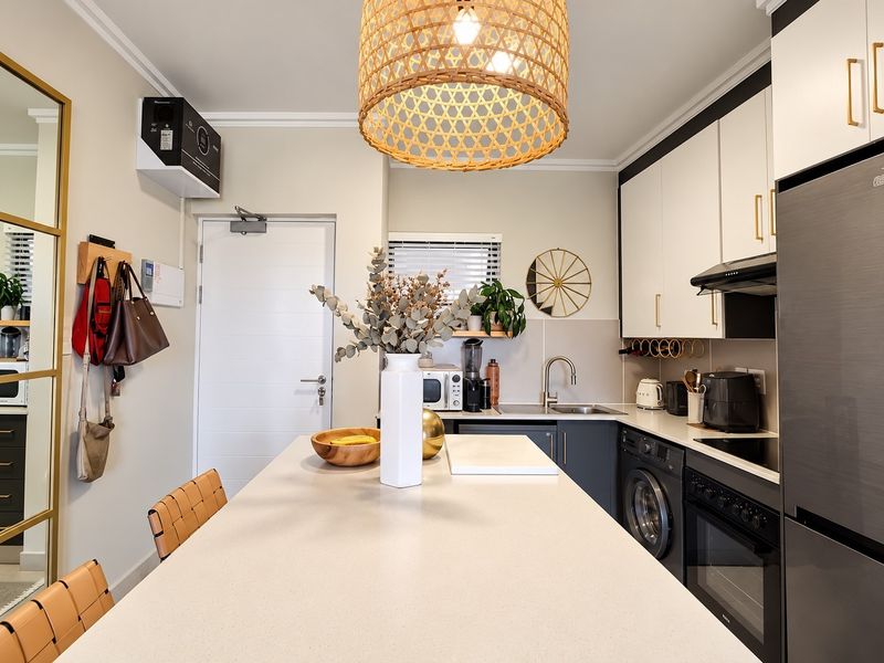 Modern kitchen featuring a central island with quartz countertops, integrated appliances, sleek cabinetry, and a functional layout with a tiled backsplash.