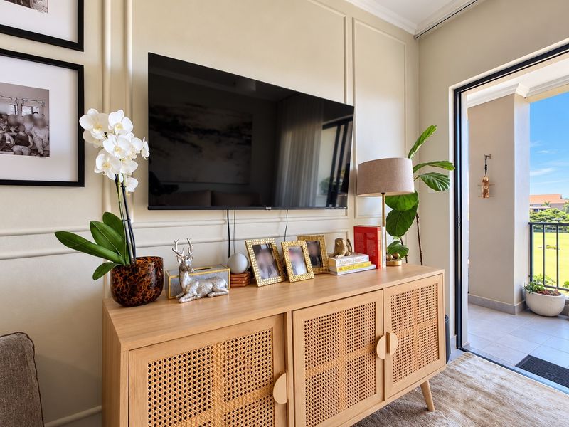 A well-maintained living area featuring elegant wainscoting and a sliding glass door that opens onto a balcony with scenic views.